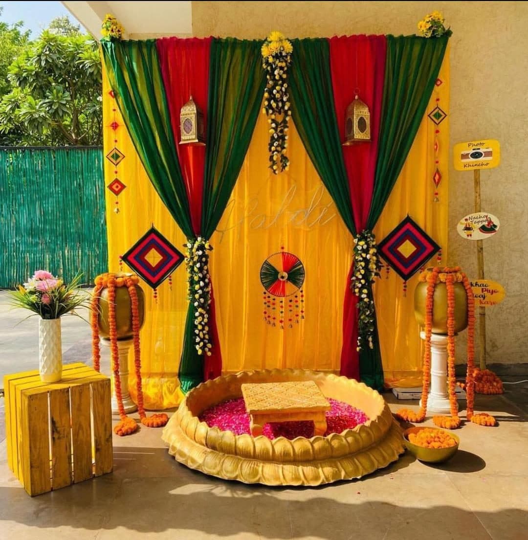 Haldi ceremony round stage with yellow, red and green drapery