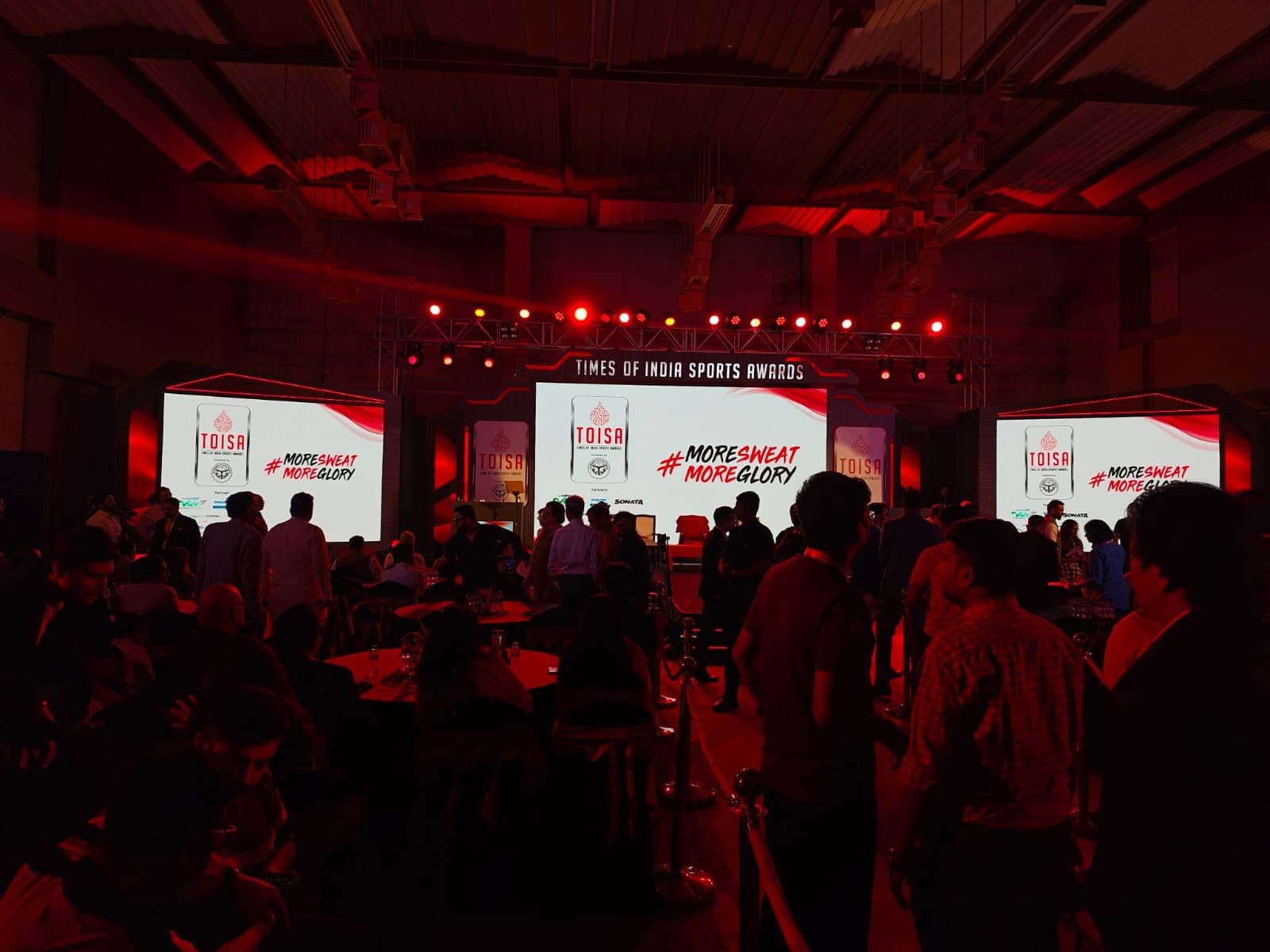 A large-scale live event stage lit in red with a packed crowd and full production rig
